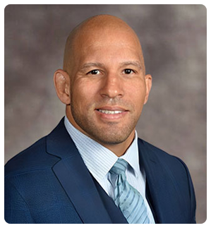 Headshot of a smiling bald man in a blue suit and tie, labeled Raphael Davis, Esq